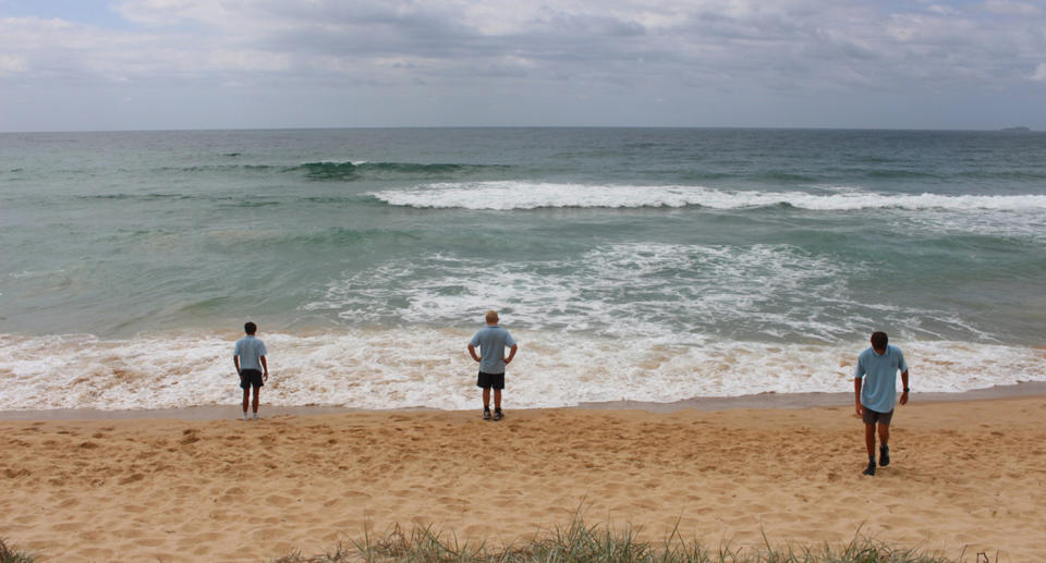 Three schoolboys look out at the surf on Woolgoolga Back Beach.