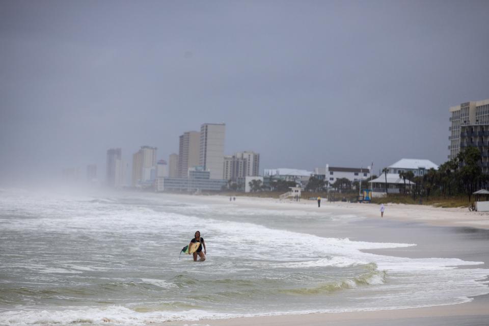 A person holds a surfboard on Panama City Beach before Helene’s landfall on Thursday (REUTERS/Kathleen Flynn)