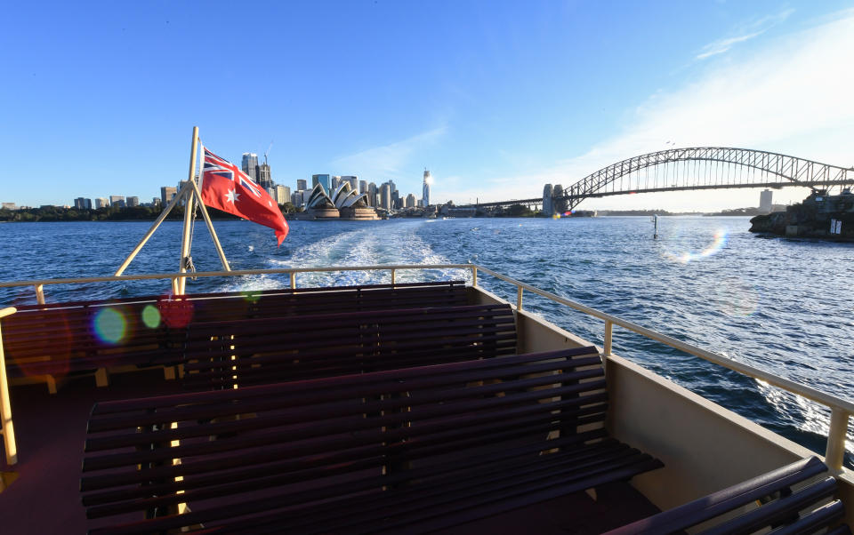 SYDNEY, AUSTRALIA - MAY 19: A ferry departs circular Quay passing the Harbour Bridge and Opera House as it heads to Neutral Bay on May 19, 2020 in Sydney, Australia. Strict social distancing measures have been introduced for public transport as Sydneysiders begin to travel around the city again as COVID-19 restrictions ease in Australia. Capacity on buses, trains, ferries and light rail will be significantly reduced with only 12 people will be allowed on a bus and 32 in a train carriage as the NSW government works to maintain strict physical distancing of 1.5 metres on the network. Green stickers on seats will indicate where commuters can sit at a safe distance. Temporary car parking zones and cycle ways across Sydney's inner city will also be set up to encourage commuters to bike or drive to work.  (Photo by James D. Morgan/Getty Images)