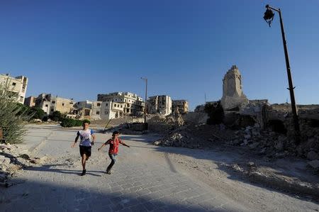 Boys run near a damaged site in the old city of Aleppo, Syria July 16, 2017. Picture taken July 16, 2017. REUTERS/Omar Sanadiki