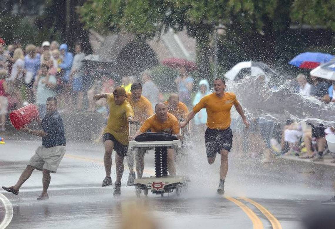 The Lowcountry Seabees team pulls a bed through a wall of water being thrown on them during a Bed Race in a past Beaufort Water Festival on Bay Street in downtown Beaufort.