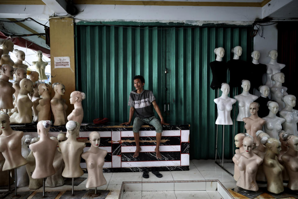 In this April 10, 2020, photo, a worker sits near mannequins at a clothing market closed due to coronavirus outbreak in Jakarta, Indonesia. While its neighbors scrambled early this year to try to contain the spread of the new coronavirus, the government of the world’s fourth most populous nation insisted that everything was fine. Only after the first cases were confirmed in March did President Joko Widodo acknowledge that his government was deliberately holding back information about the spread of the virus to prevent the public from panicking. The country now has the the highest death toll in Asia after China. (AP Photo/Dita Alangkara)