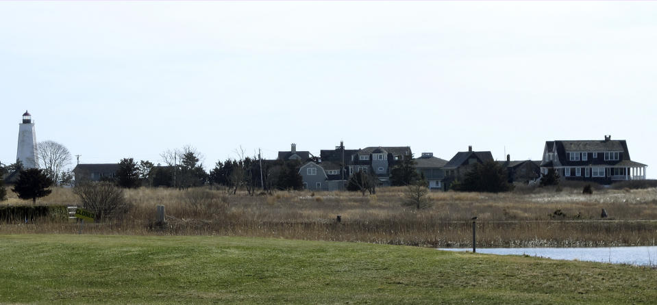 In this April 2, 2019 photo, multimillion-dollar homes and a lighthouse sit on a peninsula in Old Saybrook, Conn. The homes are among more than 900 structures on the East Coast that would become newly eligible for federal disaster aid, under a proposed remapping of coastal protection zones by the U.S. Fish & Wildlife Service. (AP Photo/Dave Collins)