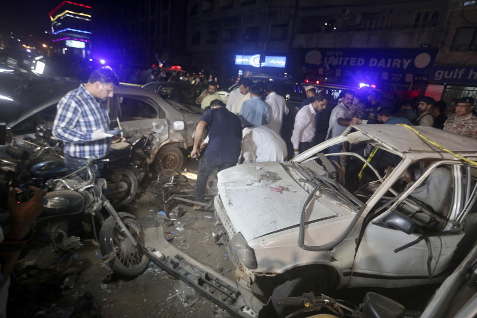 Pakistani investigator examine the site of bomb explosion, in Karachi, Pakistan, Thursday, May 12, 2022. A roadside bombing targeted a van carrying Pakistani security forces in the southern port city of Karachi on Thursday, killing and wounding few people, police said. (AP Photo/Fareed Khan)