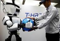 An employee of Toyota Motor Corp. demonstrates T-HR3 humanoid robot which will be used to support the Tokyo 2020 Olympic and Paralympic Games, during a press preview in Tokyo