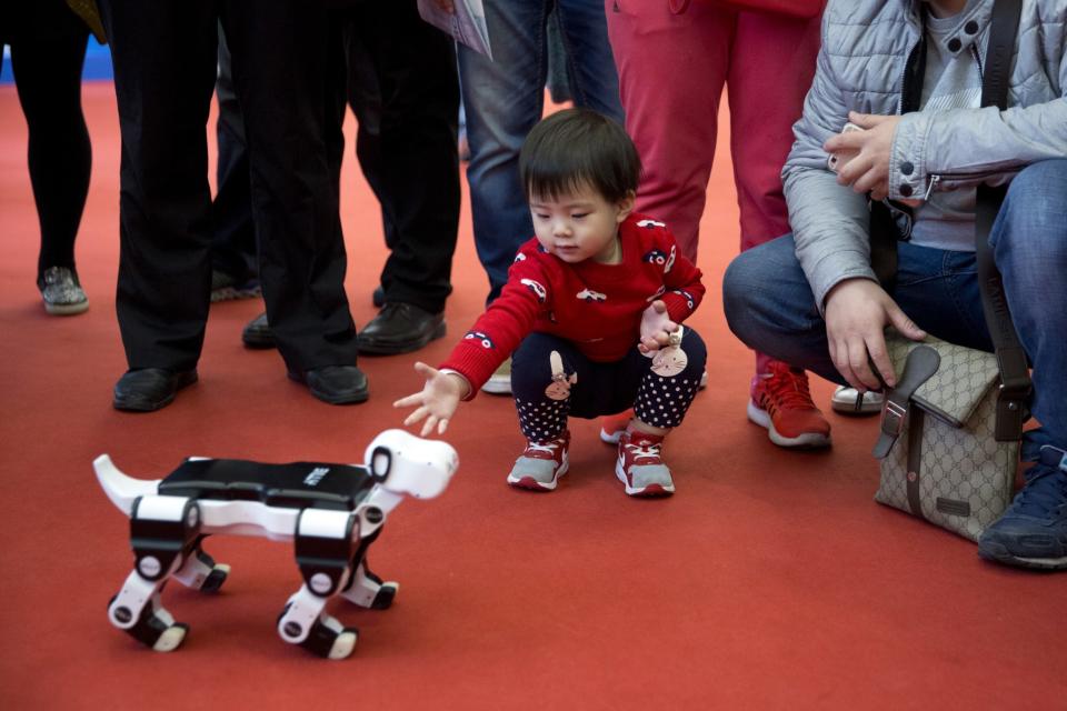 <p>A child reaches out to pat a robotic dog at the World Robot Conference in Beijing, China. (AP Photo/Ng Han Guan) </p>