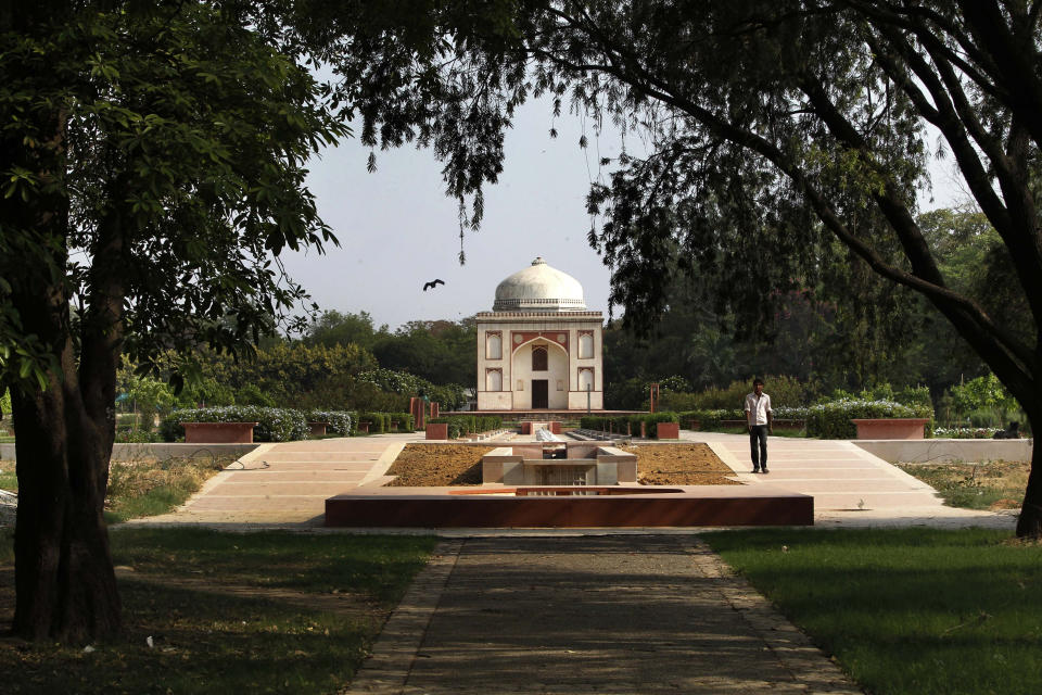 In this Wednesday, June 5, 2013 photo, a worker walks past a renovated tomb inside Sunder Nursery, a 100-acre field founded by British colonists to grow experimental plants, in New Delhi. (AP Photo/Manish Swarup)