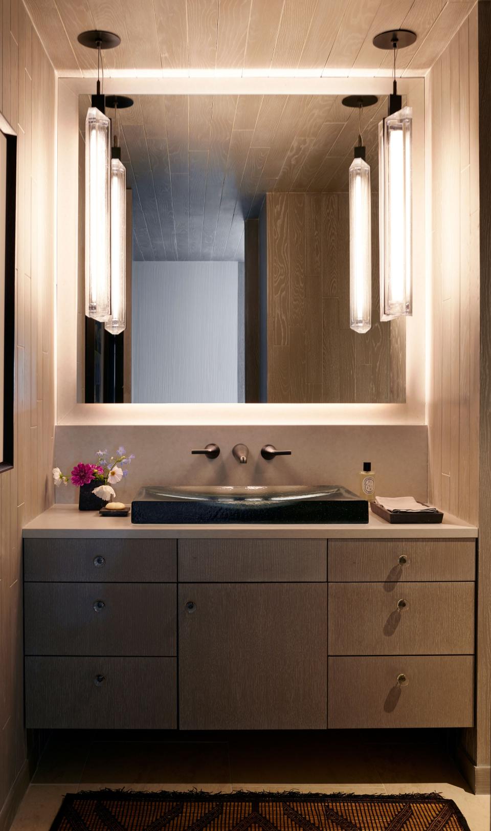 This powder room got a light makeover: An existing vanity was refinished by La Polla Designs and topped with a Kohler Antilia Wading Pool glass sink. The pendants are from Hersh Design.