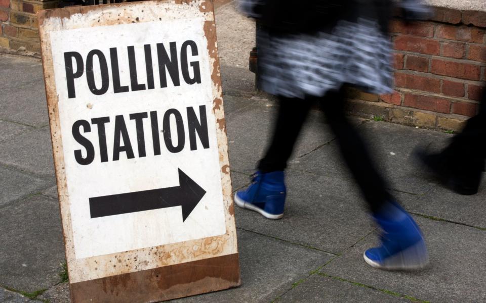 People pass a polling station sign in Brixton, south west London - Credit: HANNAH MCKAY