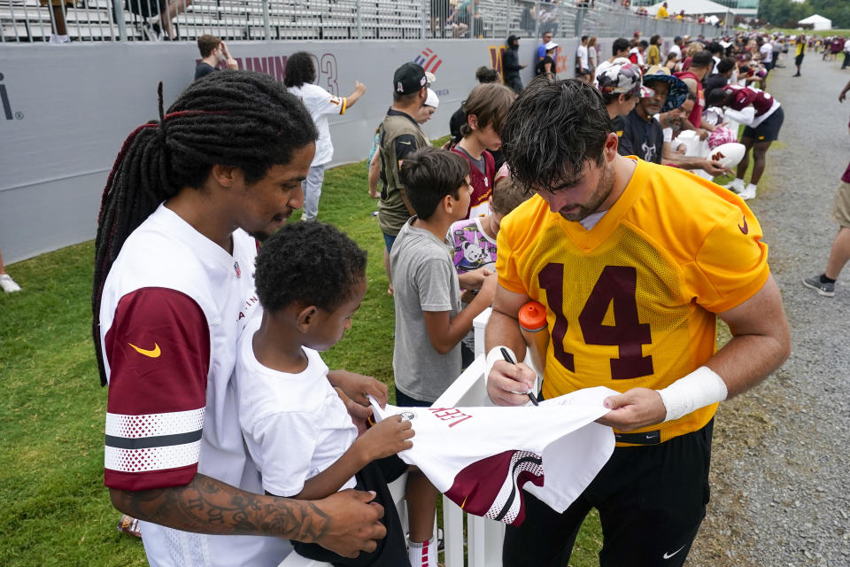 Washington Commanders quarterback Sam Howell (14) signs an autograph for a fan after an NFL football practice at the team's training facility, Thursday, July 27, 2023, in Ashburn, Va. (AP Photo/Alex Brandon)
