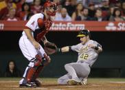 Oakland Athletics' Josh Reddick, right, scores on a single by Eric Sogard as Los Angeles Angels catcher Chris Iannetta watches for a throw during the third inning of a baseball game on Tuesday, April 15, 2014, in Anaheim, Calif. (AP Photo/Jae C. Hong)