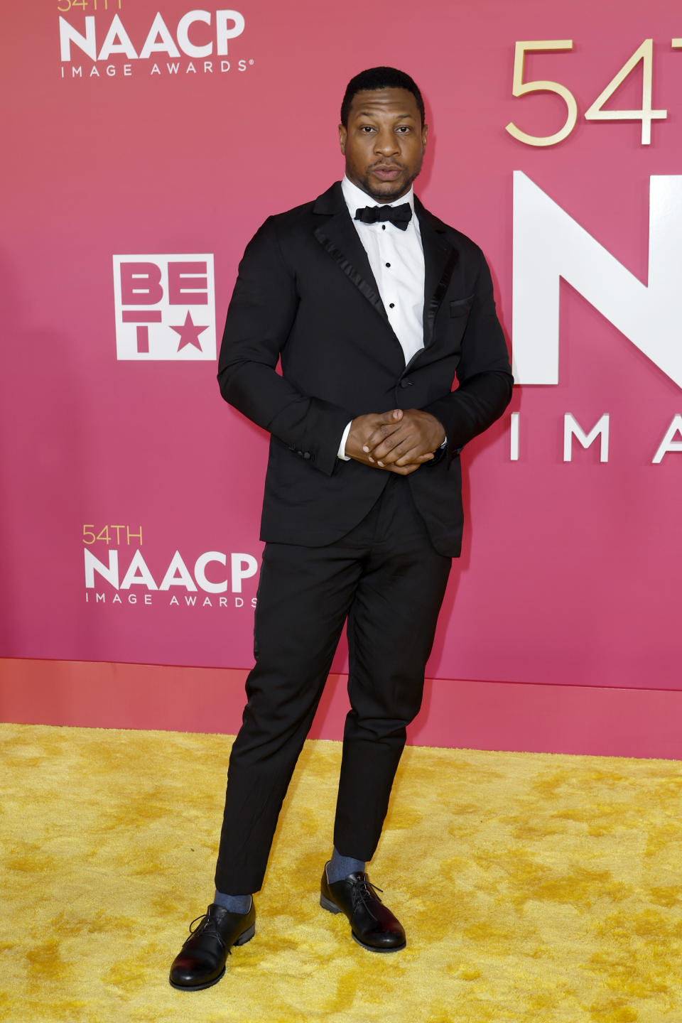 Jonathan Majors wearing a black tuxedo.