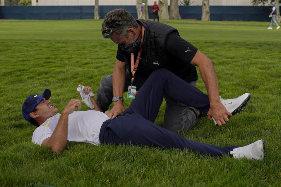 Brooks Koepka gets treated for an injury on the 12th hole during the second round of the PGA Championship golf tournament at TPC Harding Park Friday, Aug. 7, 2020, in San Francisco. (AP Photo/Jeff Chiu)