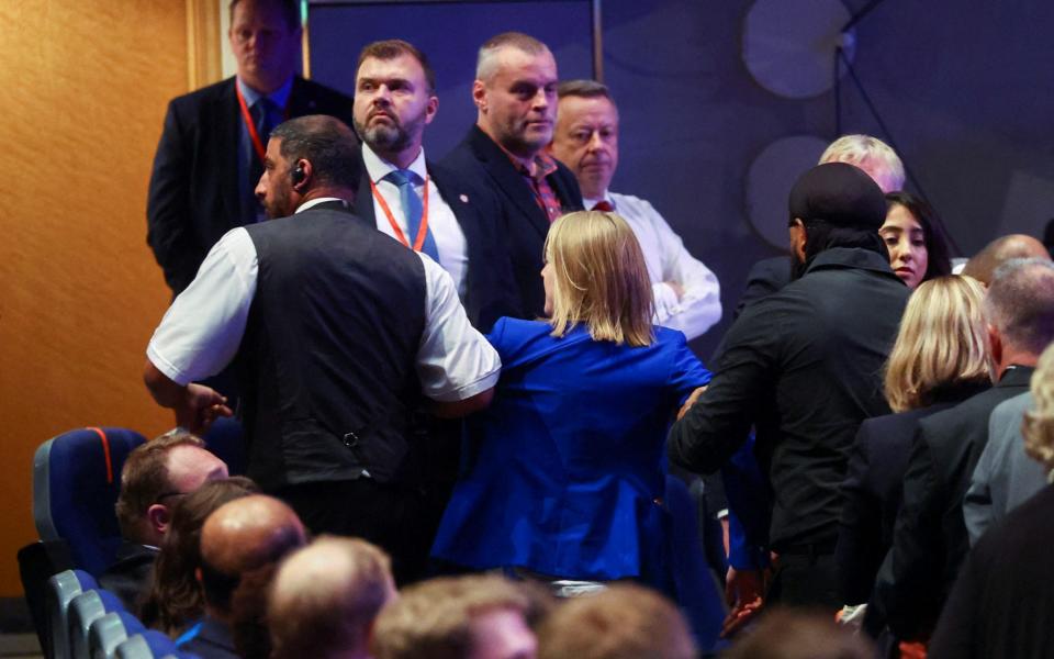 A protester is escorted out of the conference hall - HANNAH MCKAY/ REUTERS