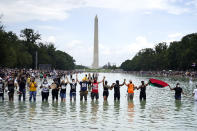 People pose for a photo in the Reflecting Pool in the shadow of the Washington Monument as they attend the March on Washington, Friday, Aug. 28, 2020, at the Lincoln Memorial in Washington, on the 57th anniversary of the Rev. Martin Luther King Jr.'s "I Have A Dream" speech. (AP Photo/Julio Cortez)