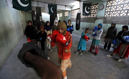 Anum, 17, punches padding with her coach Younus Qambrani while others observe during an exercise session at the first women's boxing coaching camp in Karachi, Pakistan February 20, 2016. REUTERS/Akhtar Soomro