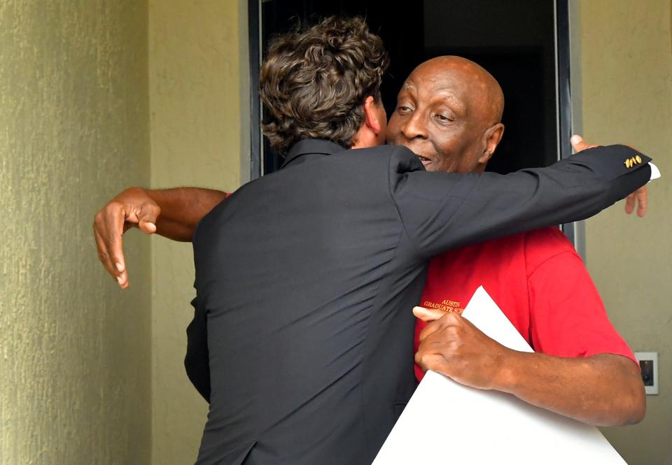 Howie Guja with the Publishers Clearing House Prize Patrol hugs Thomas Moore Sr. on his front porch after handing him an oversized $1 million prop check Wednesday afternoon.