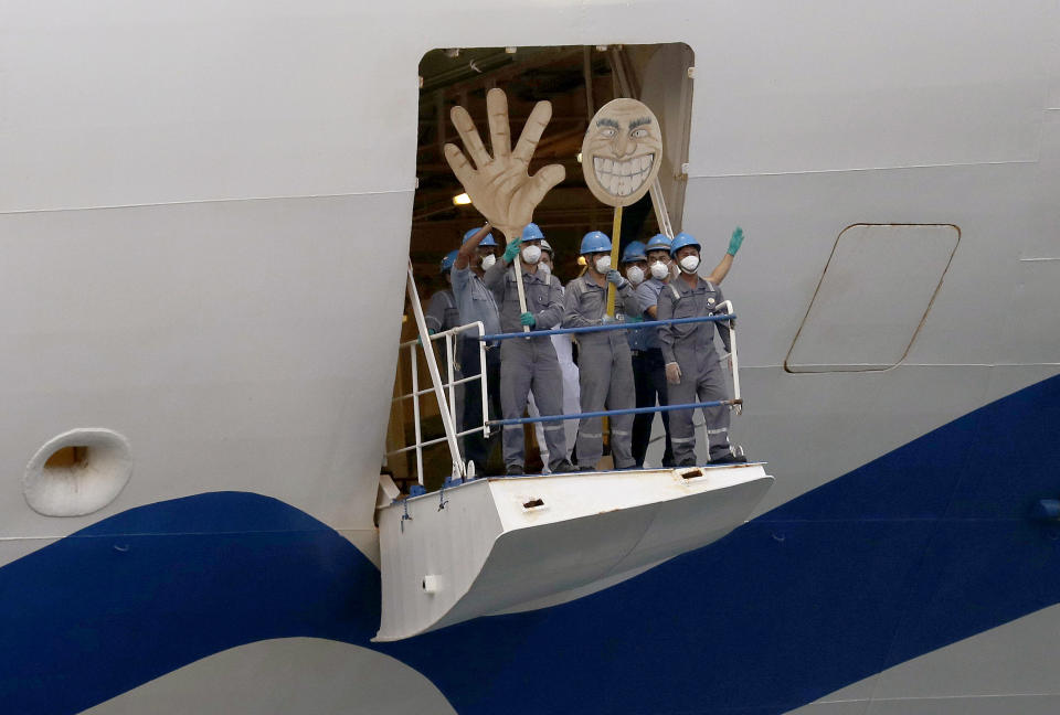 Crew on the the Ruby Princess wave with a cartoon sized hand and head as the ship departs from Port Kembla in Wollongong, Australia, Thursday, April 23, 2020. The ocean liner became notorious as Australia's largest single source of coronavirus infections and is the center of a criminal investigation over the sickness' spread set off a month after it was ordered by police to leave. (AP Photo/Rick Rycroft)