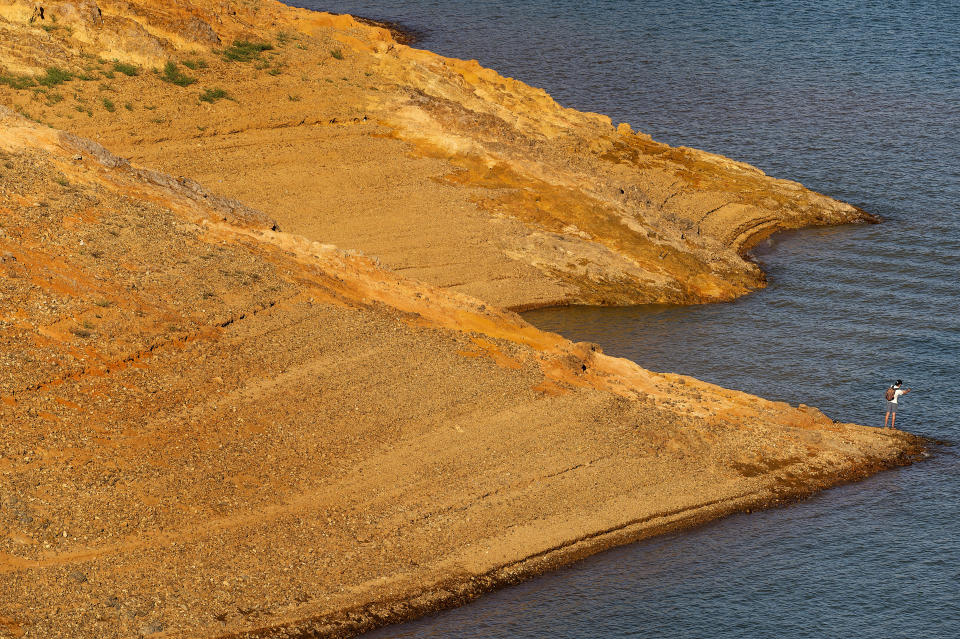 A man fishes on the banks of Shasta Lake on Sunday, May 23, 2021, in Shasta Trinity National Forest, Calif. The reservoir is at 45 percent of capacity and 52 percent of its historical average. (AP Photo/Noah Berger)