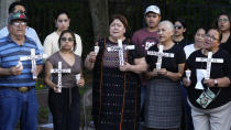 Mourners hold crosses with some of the victim's names of a bus crash during a memorial vigil at The Farmworkers Association Wednesday, May 15, 2024, in Apopka, Fla. Eight farmworkers were killed and dozens were injured when a pickup truck and bus collided early Tuesday morning in Dunnellon, Fla. (AP Photo/Chris O'Meara)