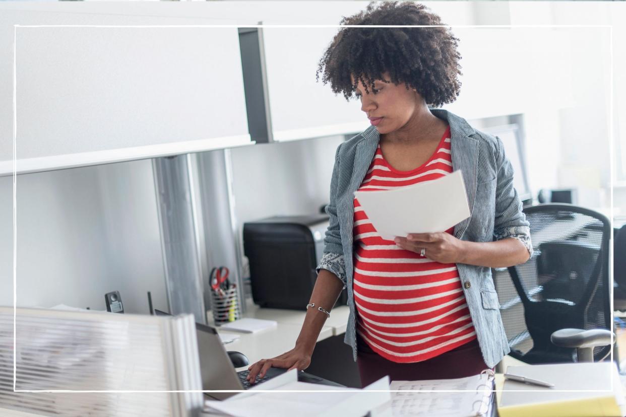  Pregnant woman in an office looking at maternity pay forms. 