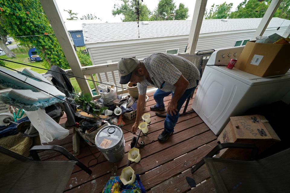 Lester Naquin clears room to sit on the porch of his home in Pointe-aux-Chenes on May 24, 2022. The house was heavily damaged by Hurricane Ida  nine months earlier.