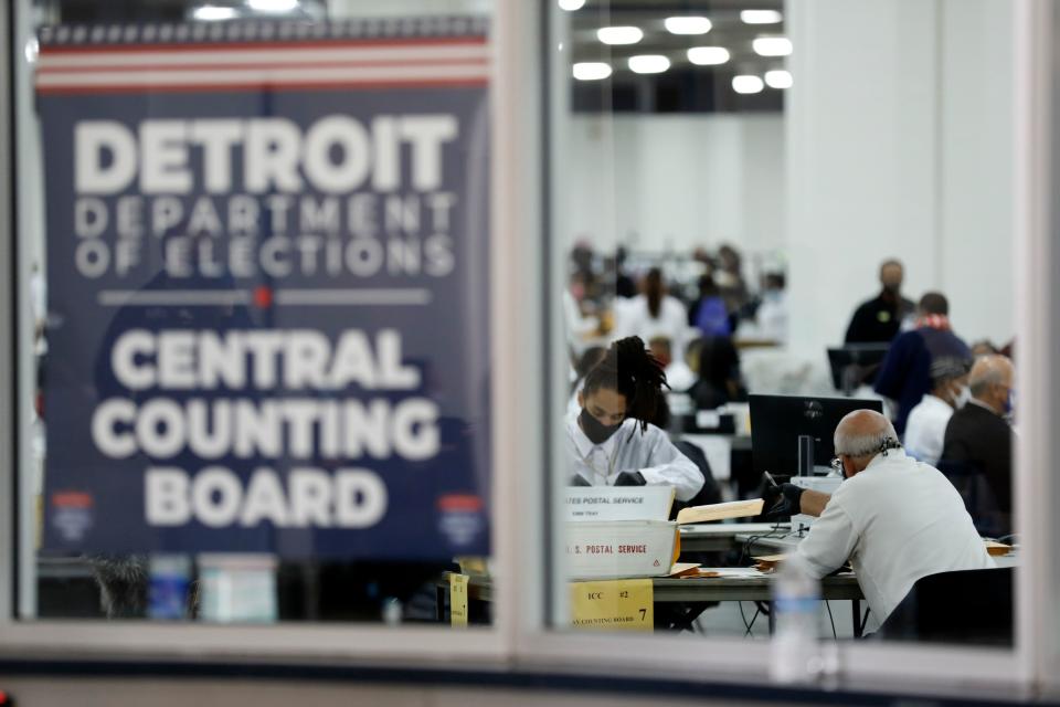 Detroit election workers count absentee ballots, seen through a window carrying a poster saying Detroit Department of Elections, Central Counting Board.