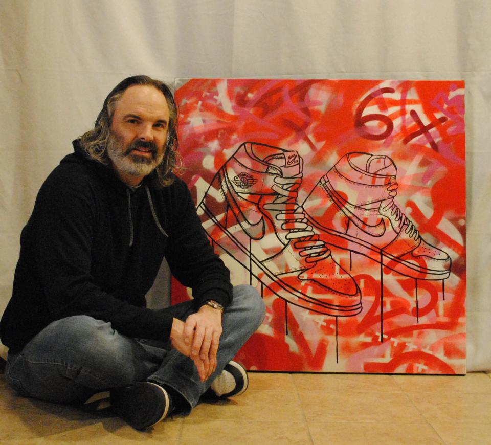 St. Louis-based graffiti pop artist David Ruggeri poses beside his painting featuring Jordan sneakers.