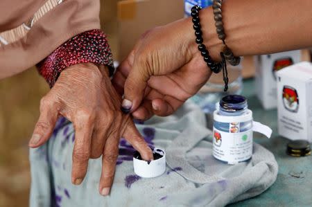 An election official helps an elderly woman to mark her finger with ink after casting her vote during regional elections in Tangerang, west of Jakarta, Indonesia June 27, 2018. REUTERS/Willy Kurniawan