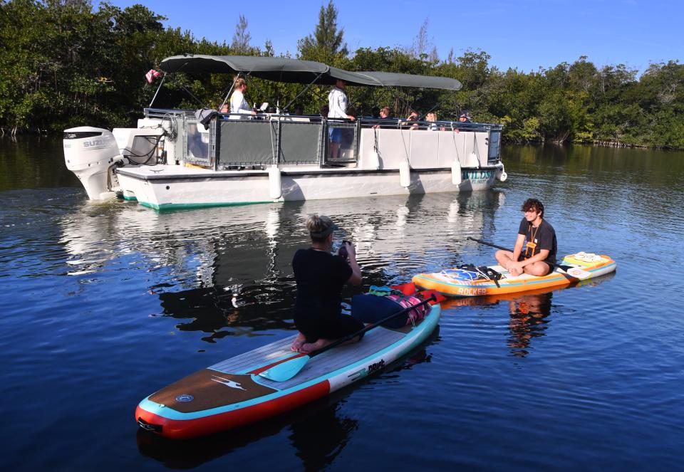 Stand up paddle boarders prepare to head out at Ramp Road park through the Thousand Islands as Wildside Tours passes by on their ecotour of the Thousand Islands