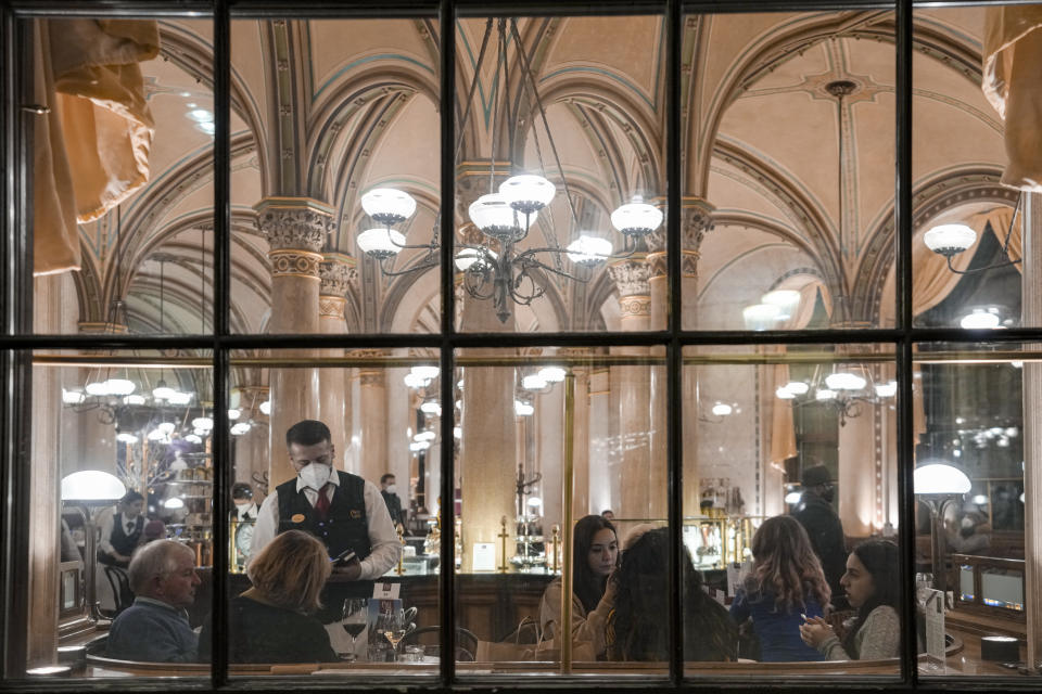 People sit in a cafe in Vienna, Austria, Sunday, Nov. 21, 2021. The Austrian government announced a nationwide lockdown that will start Monday and comes as average daily deaths have tripled in recent weeks and hospitals in heavily hit states have warned that intensive care units are reaching capacity.(AP Photo/Vadim Ghirda)