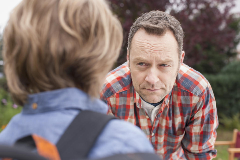 Dad crouching and looking intently at young son