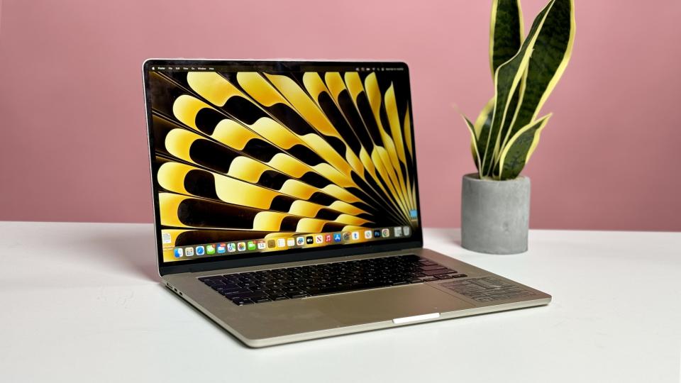MacBook Air 15 M2 in silver open on a white desk facing you with a pink wall behind it