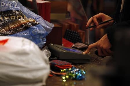 A customer signs the credit card pad as he pays for a purchase at Macy's on Black Friday in New York November 26, 2010. REUTERS/Jessica Rinaldi