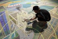 A worker paints at the exhibition stand of "Sim City" during the Gamescom 2012 fair in Cologne August 15, 2012.
