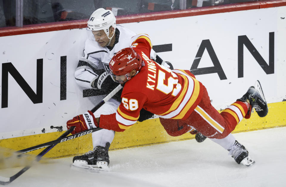 Los Angeles Kings forward Trevor Lewis (61) is checked by Calgary Flames defenseman Oliver Kylington (58) during the second period of an NHL hockey game, Tuesday, Feb. 27, 2024 in Calgary, Alberta. (Jeff McIntosh/The Canadian Press via AP)