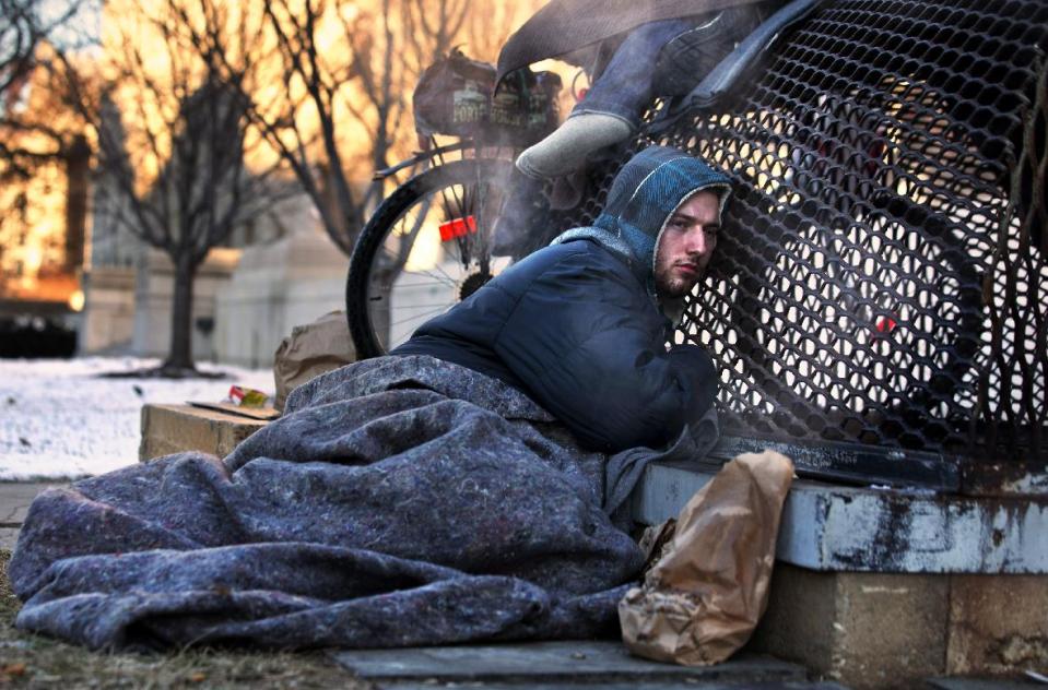 Nicholas Simmons, 20, of Greece, N.Y., warms himself on a steam grate with three homeless men by the Federal Trade Commission, just blocks from the Capitol, during frigid temperatures in Washington, Saturday, Jan. 4, 2014. On New Year’s Day, Simmons disappeared from his parents’ house in a small upstate New York town, leaving behind his wallet, cellphone and everything else. Four days later, an Associated Press photographer, looking for a way to illustrate unusually cold weather, took his picture as he warmed himself on a steam grate a few blocks from the U.S. Capitol. His parents Paul and Michelle Simmons saw the photograph in USA Today Sunday morning after it was brought to their attention through a Facebook page set up to help find their son, according to police and family friends, and were able to report his location to D.C. police who transported him to a hospital where he was reunited with his father and brother who drove all day to find him. (AP Photo/Jacquelyn Martin))