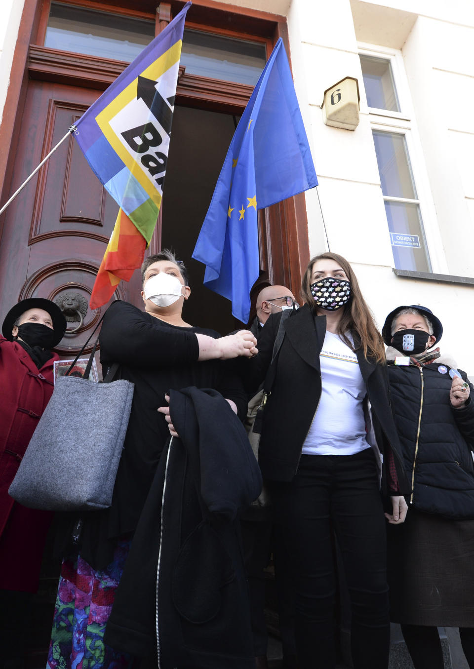 Polish activists Elzbieta Podlesna, left, and Anna Prus surround by supporters as they leave court after being acquitted of desecration by a court in Plock, Poland, Tuesday March 2, 2021. A Polish court has acquitted three activists who had been accused of desecration for adding the LGBT rainbow to images of a revered Roman Catholic icon. In posters that they put up in protest in their city of Plock, the activists used the rainbow in place of halos on a revered image of the Virgin Mary and baby Jesus. (AP Photo/Czarek Sokolowski)
