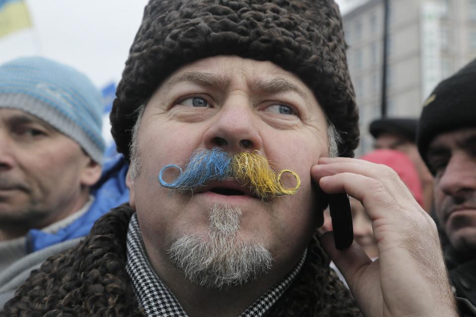 FILE - In this Sunday, Dec. 15, 2013 file photo a Pro-European Union supporter, with his mustaches painted in yellow-and-blue Ukrainian national flag colors, attends a mass rally in Kiev Ukraine. After two months of anti-government protests, modern Ukraine has never been so bitterly polarized. To be sure, Ukraine has long been divided. Russia and Europe have vied for dominance for centuries, causing deep cultural differences between the mostly Ukrainian-speaking western and central regions on the one hand, and the Russian-speaking east and south on the other. But as the crisis has deepened, each side has grown stronger in its convictions, and those who stood in the middle have been forced to choose sides. (AP Photo/Efrem Lukatsky, file)