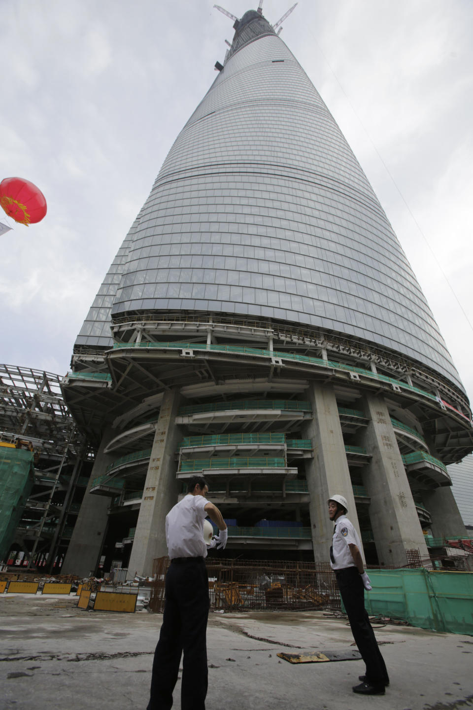 Security guards stand at the bottom of the Shanghai Tower under construction prior to the topping off ceremony in Shanghai, China, Saturday, Aug. 3, 2013. The Shanghai Tower is set to become the tallest building in China which is planned to be complete in 2014. (AP Photo/Eugene Hoshiko)