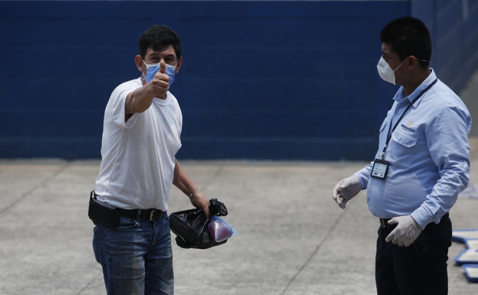 A deported man gives a thumbs up to his family who brought him food, at the site where Guatemalans returned from the U.S. are being held in Guatemala City, Friday, April 17, 2020. Recently deported Guatemalans were placed in a athletic dorm facility to wait for the results of their tests for the new coronavirus. (AP Photo/Moises Castillo)