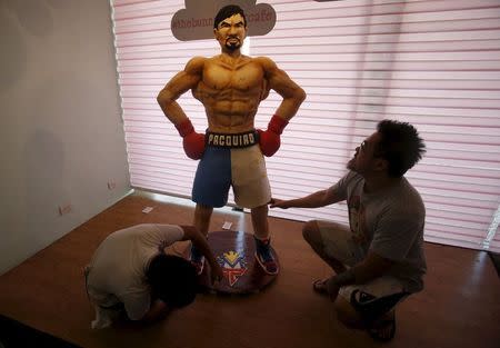 Baker Zach Yonson (R) and an assistant put finishing touches on a life-size 70-kg chocolate cake of local boxing icon Manny Pacquiao at a restaurant in Manila, Philippines May 2, 2015. REUTERS/Erik De Castro