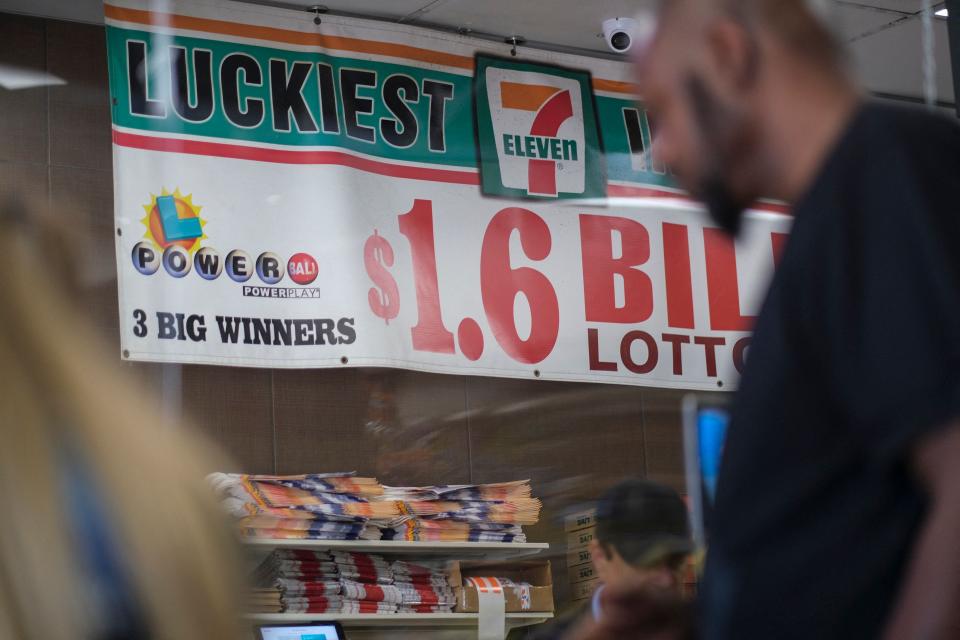 Ein Banner mit der Aufschrift „Glücklichste 7-Eleven der Welt“ hängt in einem 7-Eleven-Laden, in dem sich Menschen anstellen, um Mega Millions-Lotterielose zu kaufen, in Chino Hills, Kalifornien, am 28. Juli 2022, sechs Jahre nachdem ein Gewinnschein verkauft wurde für den größten Jackpot in der US-Lotteriegeschichte.