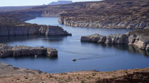 FILE - A boat cruises along Lake Powell near Page, Ariz., on July 31, 2021. Seven states in the U.S. West are facing a deadline from the federal government to come up with a plan to use substantially less Colorado River water in 2023. The U.S. Bureau of Reclamation is expected to publish hydrology projections on Tuesday, Aug. 16, 2022, that will trigger agreed-upon cuts to states that rely on the river. Prolonged drought, climate change and overuse are jeopardizing the water supply that more than 40 million people rely on. (AP Photo/Rick Bowmer, File)