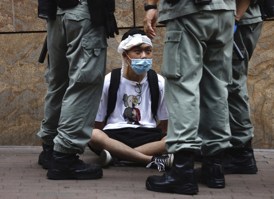 Riot police guard detain a protester as a second reading of a controversial national anthem law takes place in Central district, Hong Kong, Wednesday, May 27, 2020. Hong Kong police massed outside the legislature complex Wednesday, ahead of debate on a bill that would criminalize abuse of the Chinese national anthem in the semi-autonomous city. (AP Photo/Kin Cheung)