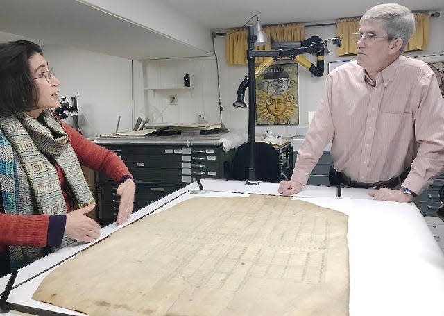 Paper conservator Janice Ellis, left, explains to Washington County Historical Society President Bill Maharay her process for restoring and conserving an early plat for the city of Hagerstown.