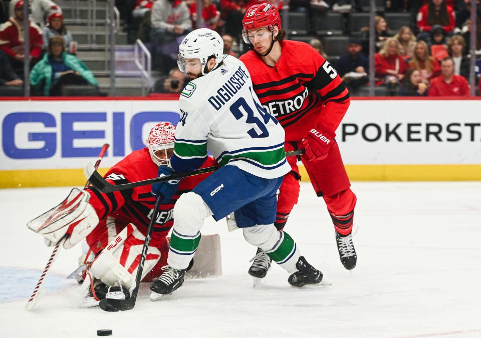 Detroit Red Wings goaltender Ville Husso makes a save as defenseman Moritz Seider defends Vancouver Canucks left wing Phillip Di Giuseppe during the first period at Little Caesars Arena, Feb. 11, 2023.