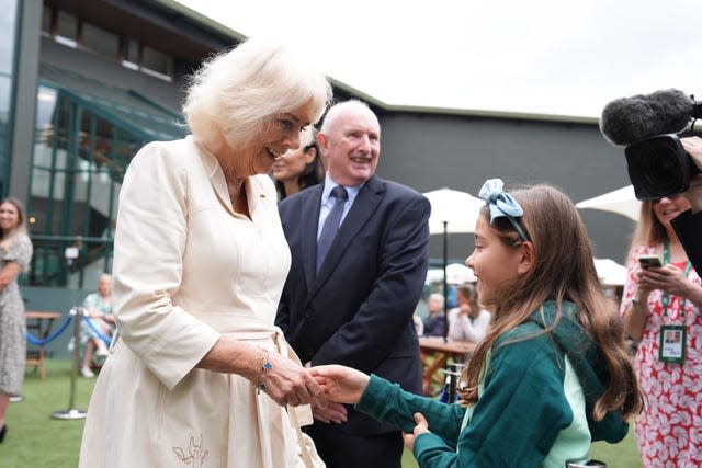 Queen Camilla shakes hands with Camila, the young daughter of Mexican tennis player Santiago Gonzalez
