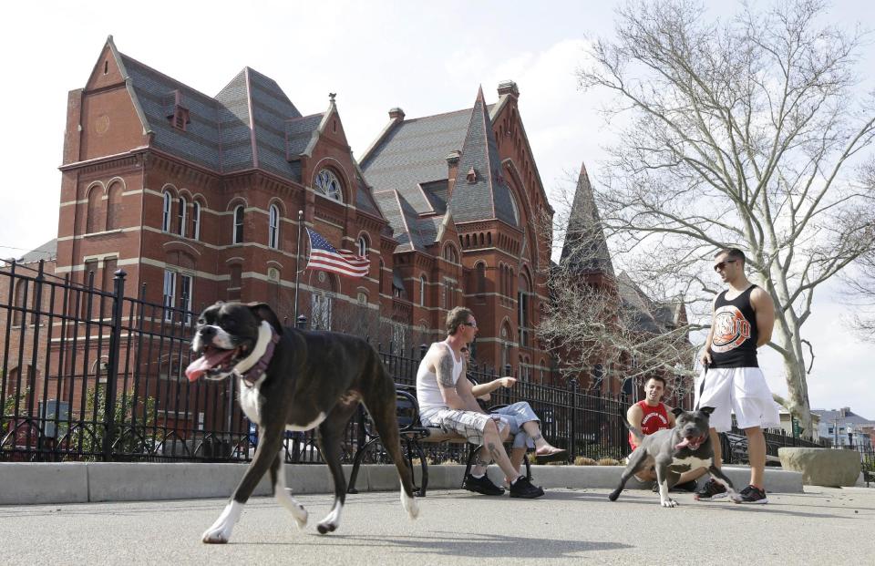 This April 10, 2013 photo shows dog owners chatting while their pets roam around the dog park located across from Music Hall at Washington Park in Cincinnati's Over-the-Rhine neighborhood. This picturesque neighborhood was named and settled by German immigrants in the 19th century, (AP Photo/Al Behrman)