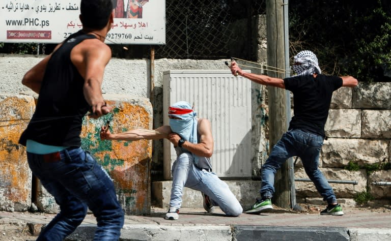 Palestinian protesters use slingshots to hurl stones towards Israeli security forces during clashes in the West Bank town of Bethlehem on April 21, 2017, in solidarity with the hunger striking prisoners